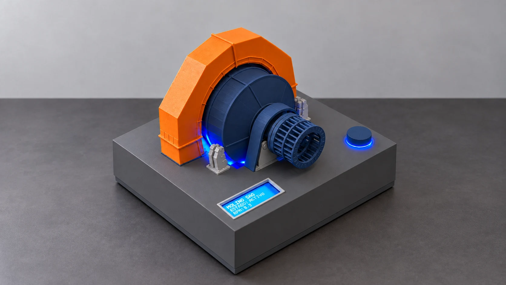 Maqueta física del molino SAG Minebox con base gris grafito y zócalo continuo, tambor y perilla azul marino mate, carcasa naranja, iluminación azul y pantalla encendida.